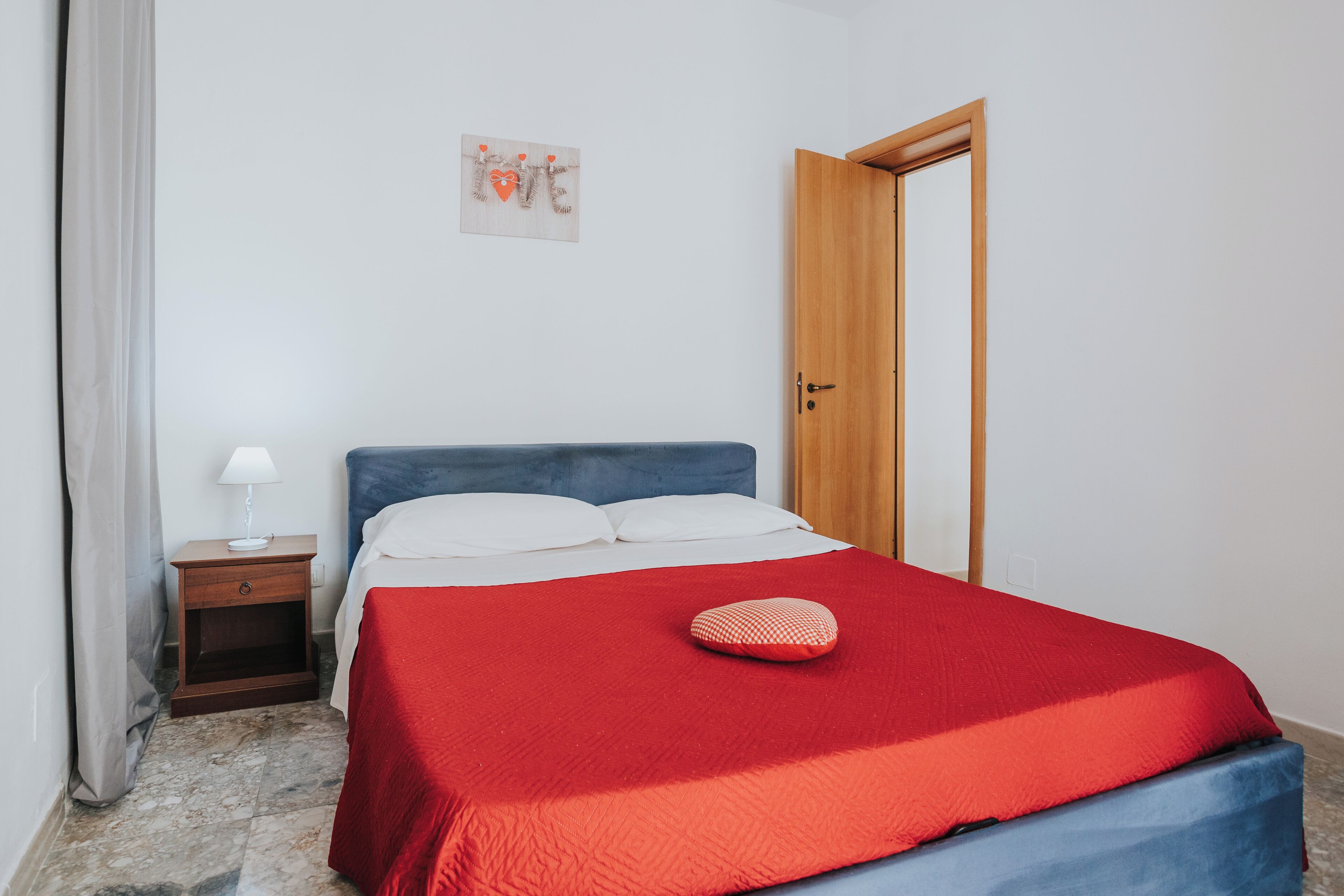 Una camera da letto con un letto, un comodino, una porta e un elemento decorativo al muro.