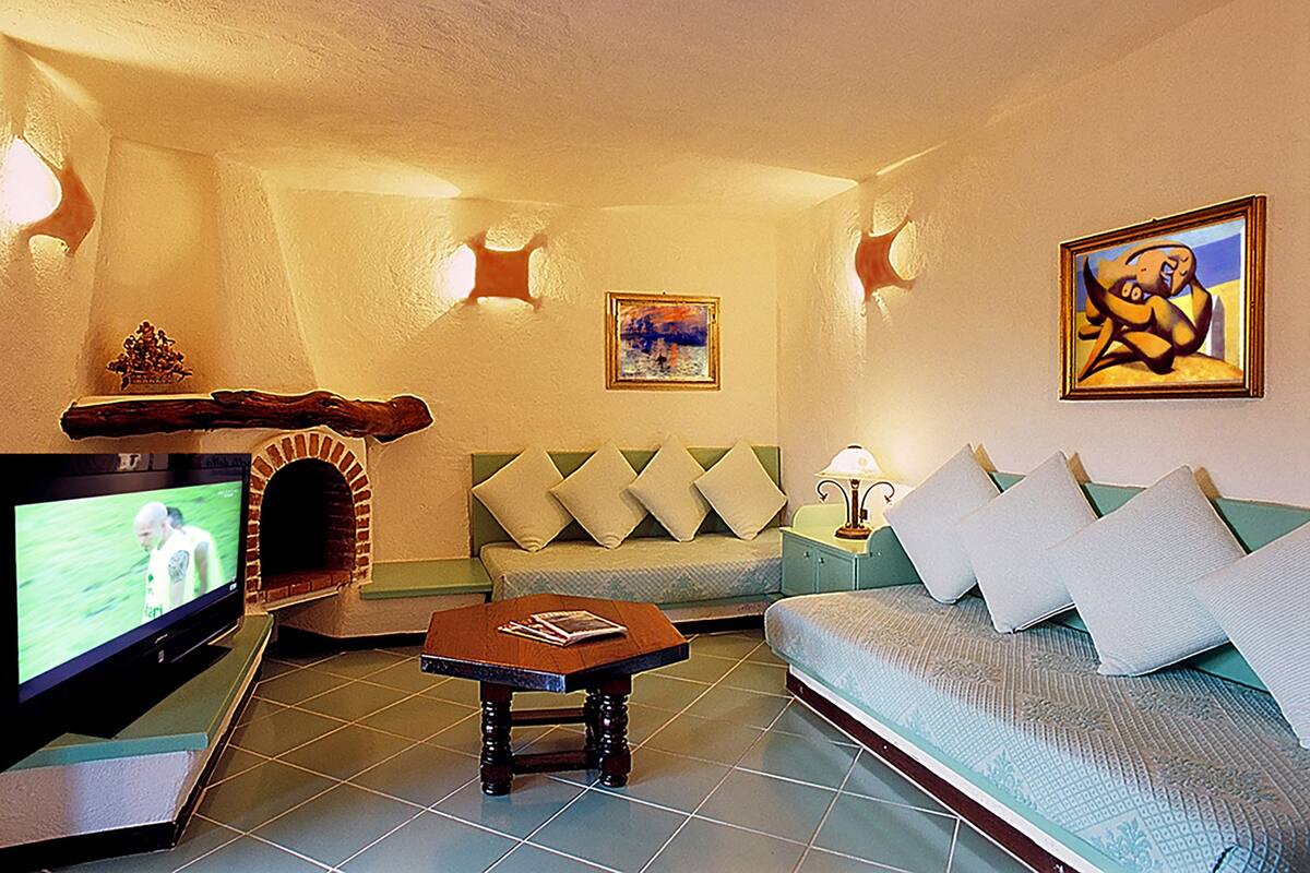 Ein gemütliches Wohnzimmer mit Fernseher, Kamin, einer Couch und Bildern an den Wänden.