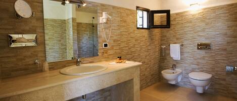 Une salle de bain avec un grand miroir, un lavabo, un bidet et des toilettes.