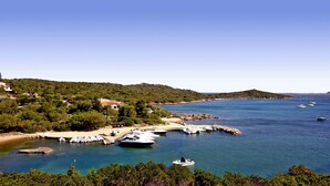 A coastal area with boats docked at a marina, surrounded by hills and greenery.