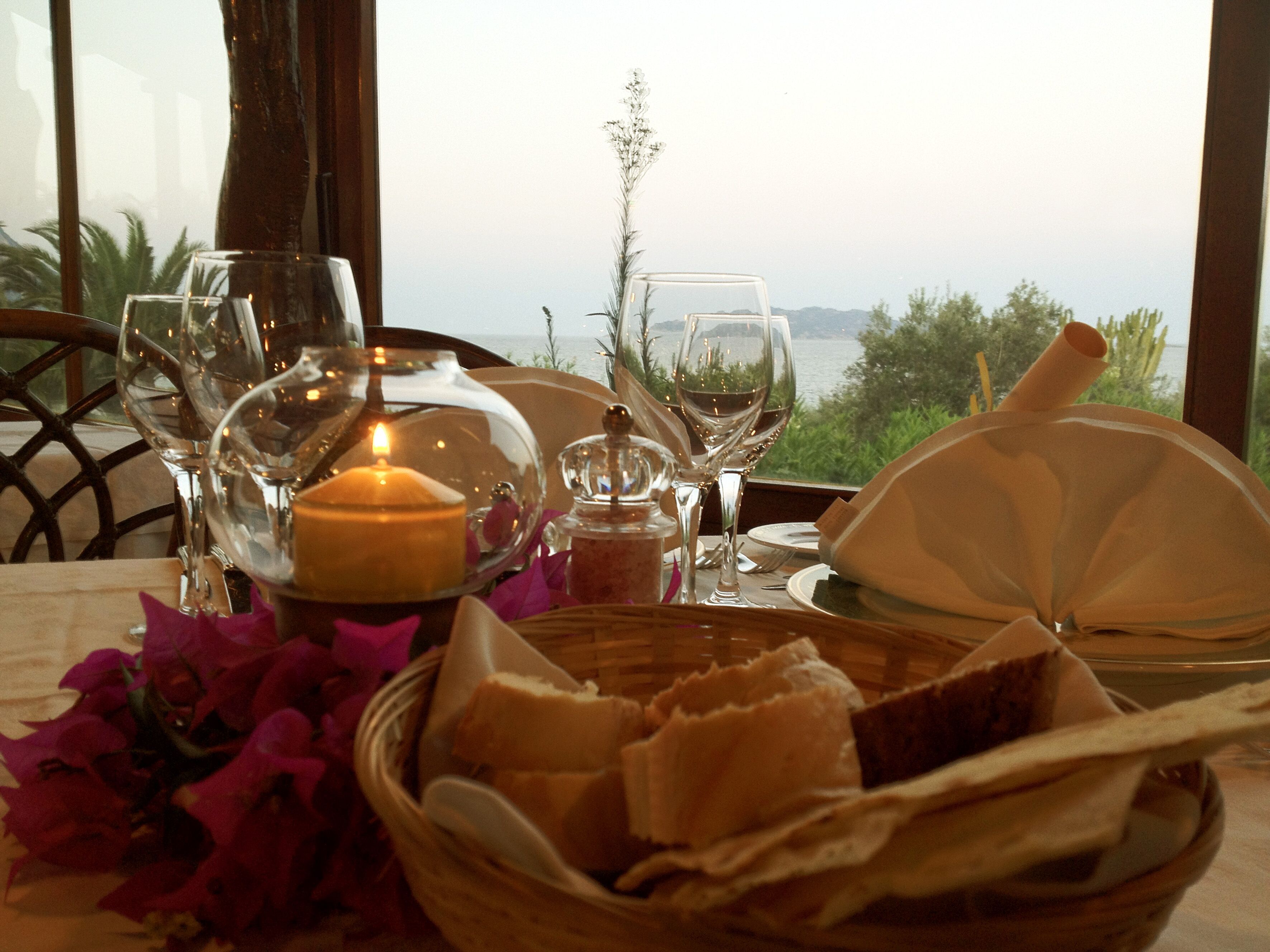 A table set for dining with wine glasses, a candle, and a basket of bread.