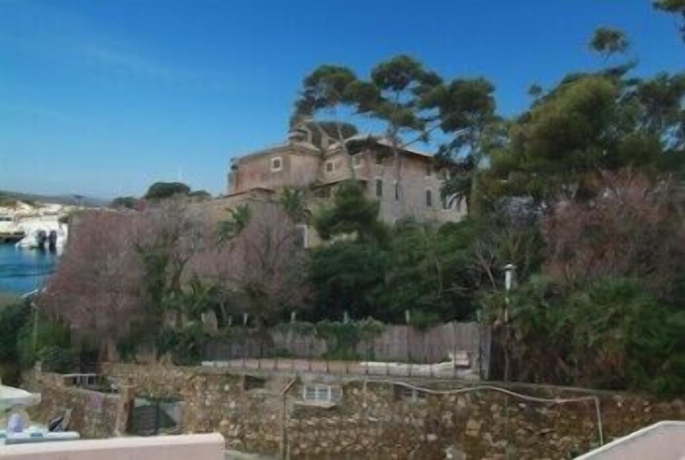 A coastal building with a stone wall and a view of the sea.