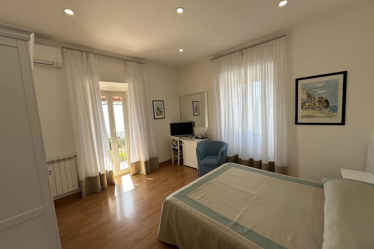 A bedroom with a bed, a desk, a chair, and a TV.