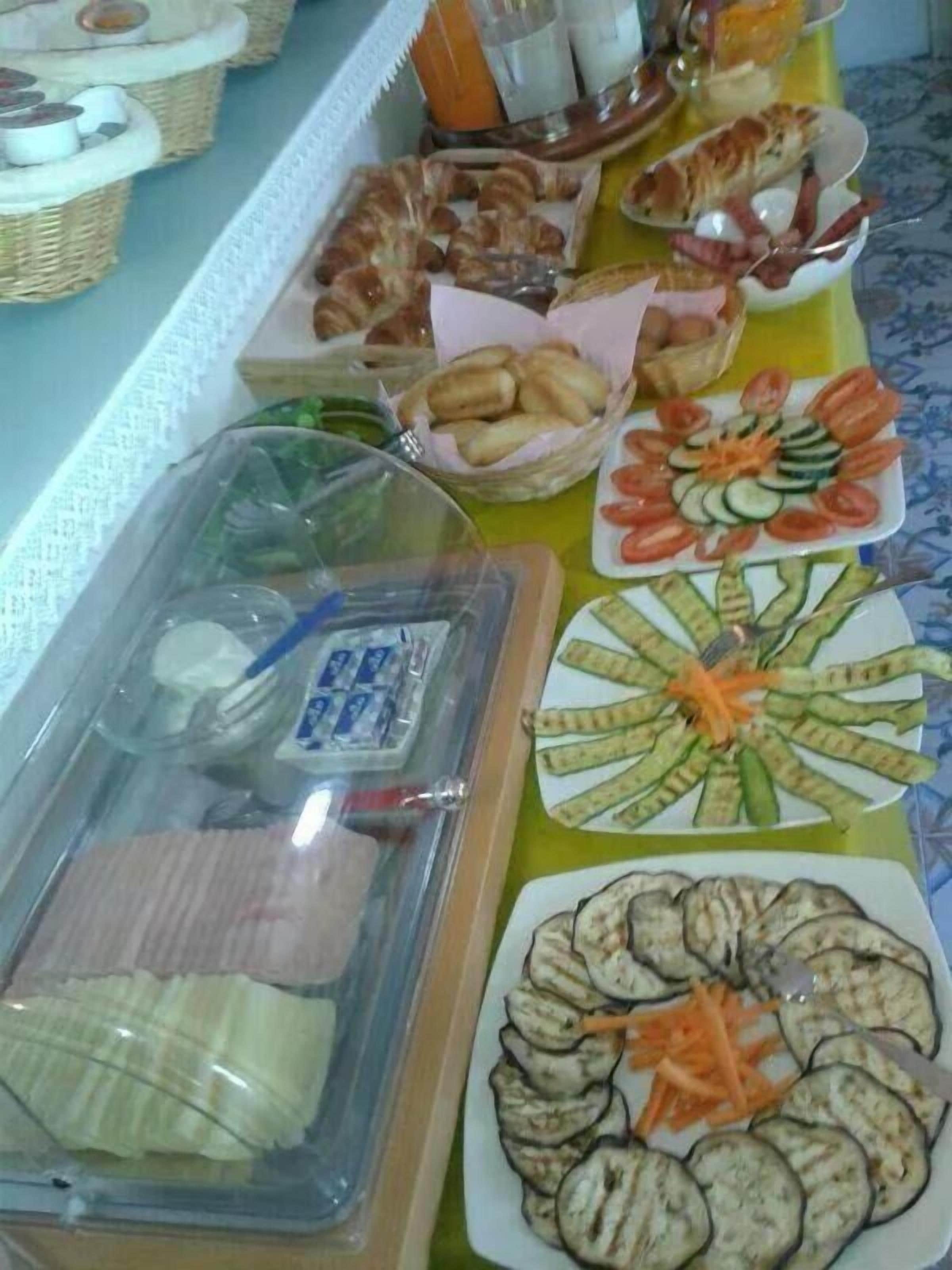 A buffet table with various food items including bread, vegetables, and meat.