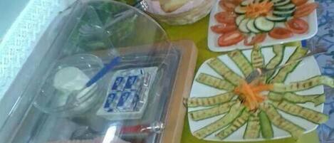 A buffet table with various food items including bread, vegetables, and meat.