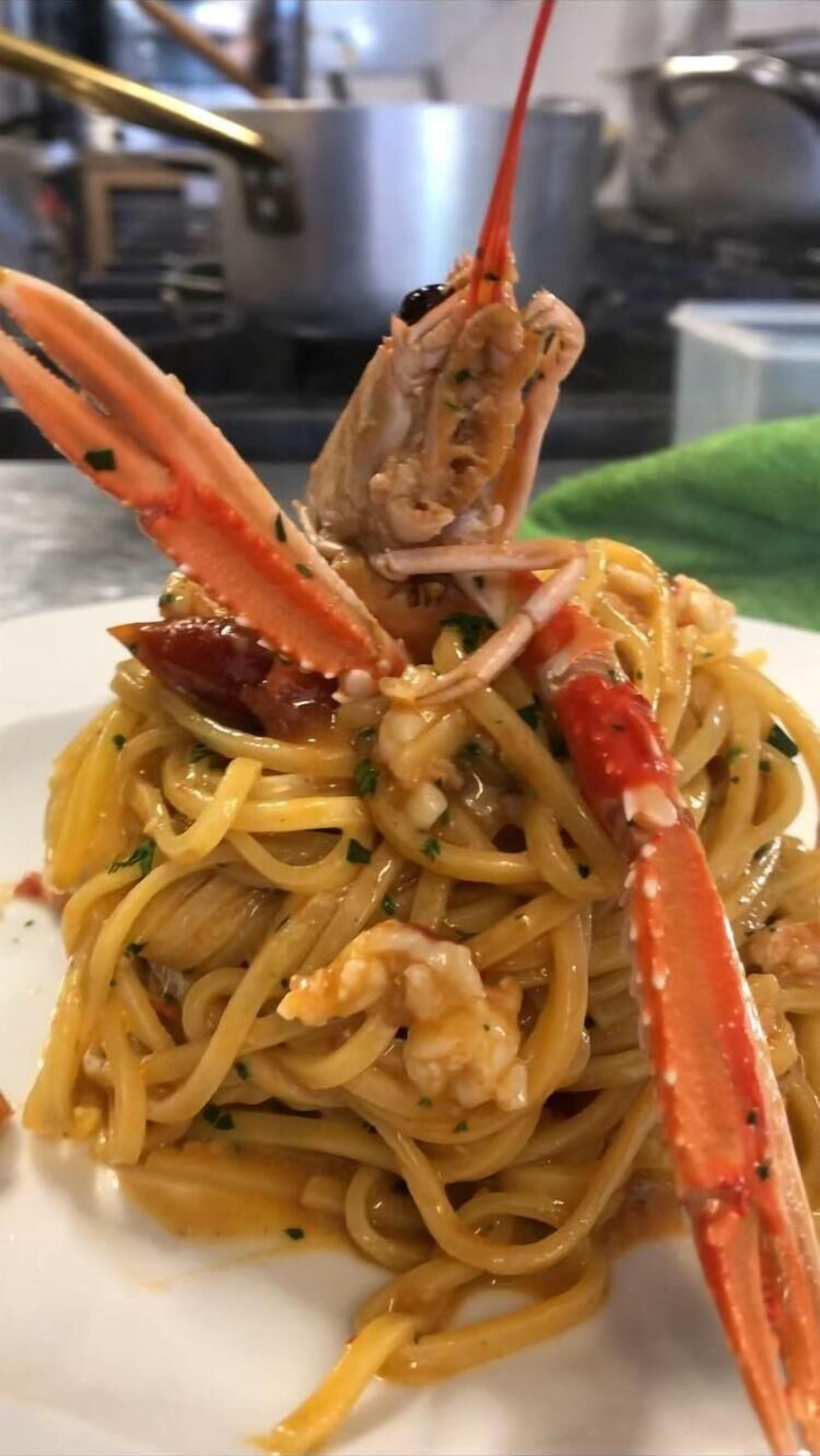 Une assiette de spaghettis surmontée d’un gros homard.