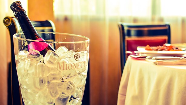A glass of Mionetto beer with a pink straw, ice cubes, and a bottle cap. - Hotel Motel Visconteo (Binasco)