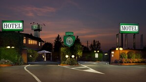 A hotel and motel with illuminated signs, a landscaped entrance, and a clear sky at dusk. - Hotel Motel Visconteo (Binasco)