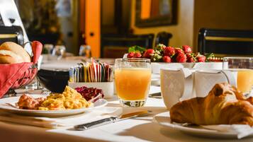 Una mesa de desayuno con cruasanes, huevos revueltos y fresas.