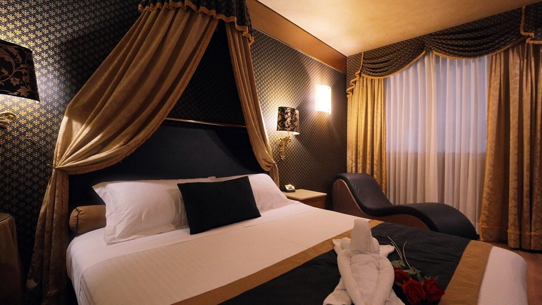 A hotel room with a large bed, a bedside table, a chair, and a window with curtains.