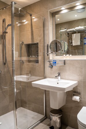 A modern bathroom with a glass-enclosed shower, a white sink, and a toilet.