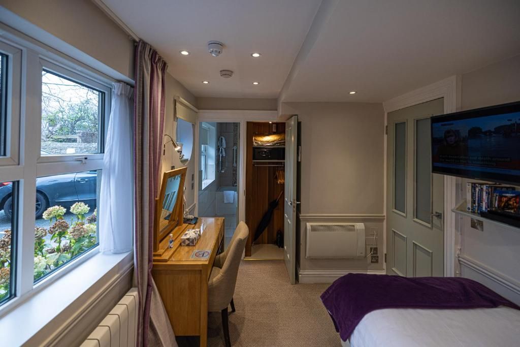 Een slaapkamer met een bed, een bureau en een raam met uitzicht op een tuin.