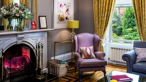 A luxurious living room with a grand chandelier, a fireplace, comfortable seating, and a view through large windows. - Roxford Lodge Hotel (Dublin)