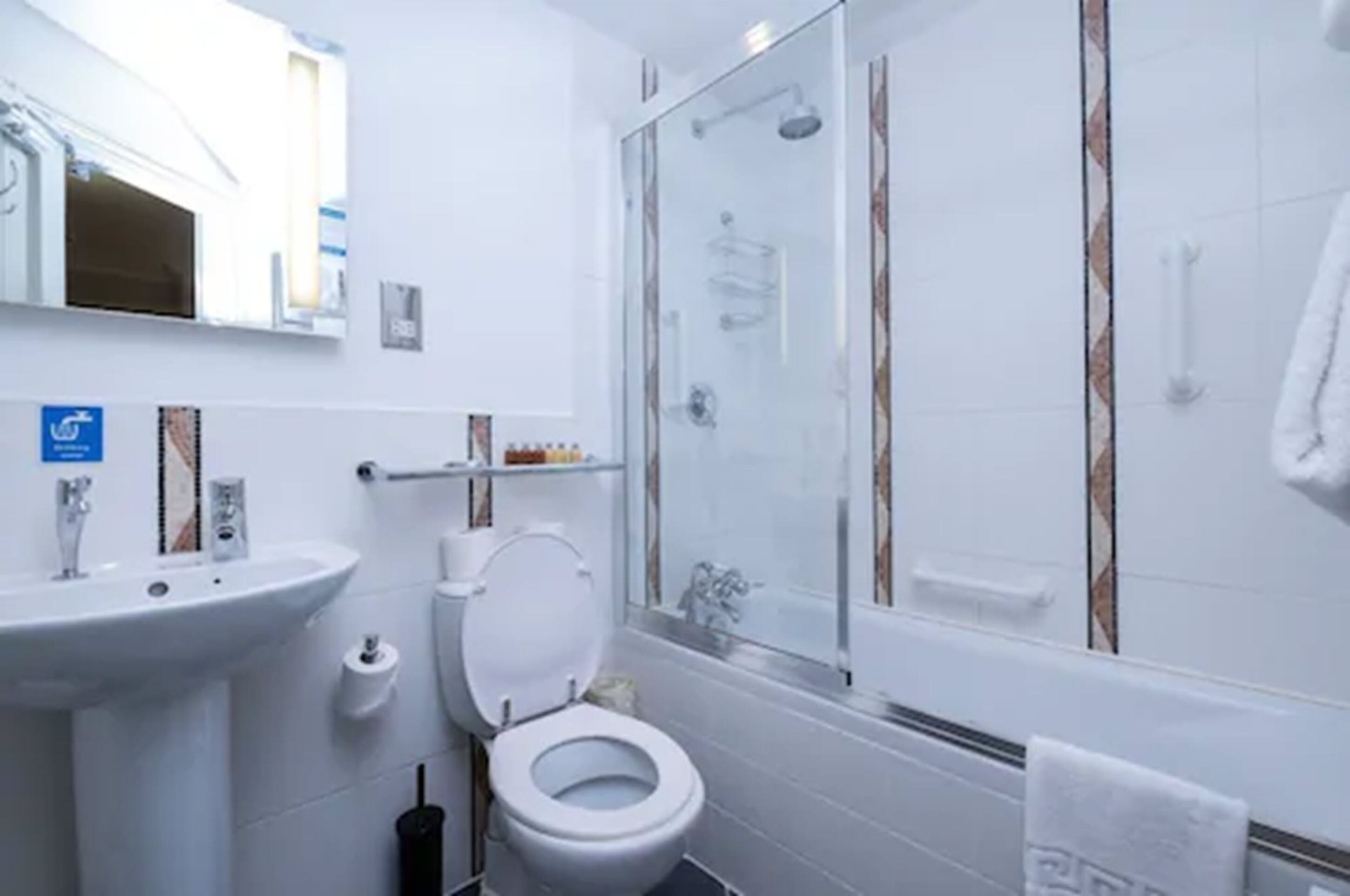 A modern bathroom with a glass-enclosed shower, a white sink, and a toilet.