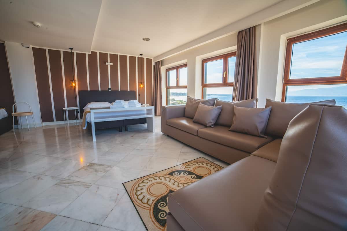Een moderne hotelkamer met een groot bed, een bank en uitzicht op zee.