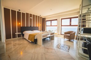 A modern hotel room with a large bed, a seating area, a view of the sea, and a balcony. - Hotel Continental (Reggio Calabria)