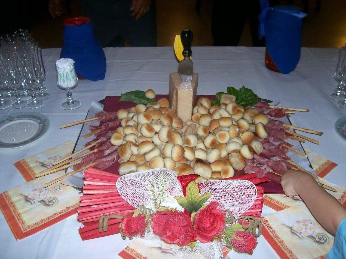 Un tavolo apparecchiato con diversi cibi, tra cui panini, spiedini di carne e un elemento decorativo al centro.
