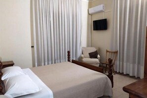 A hotel room with a bed, a chair, a TV, and curtains. - Casa del Gourmet (Siderno)