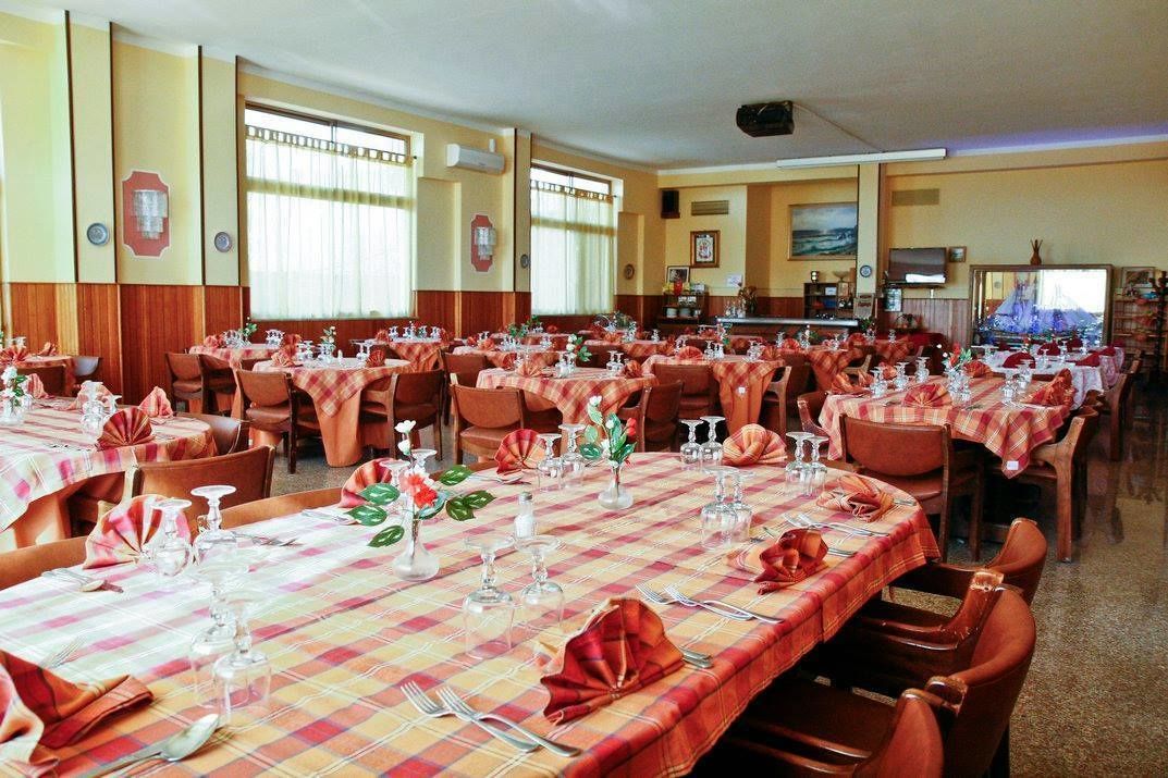 Comedor con varias mesas dispuestas para una comida, con manteles a cuadros y cubertería ordenada.