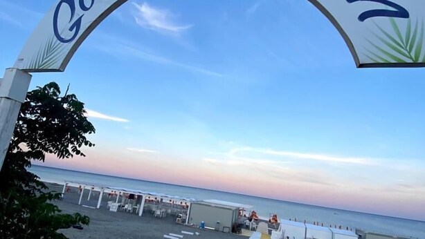 A beach entrance archway with the text "Gourmet Beach" and a pathway leading to beachside accommodations. - Casa del Gourmet (Siderno)