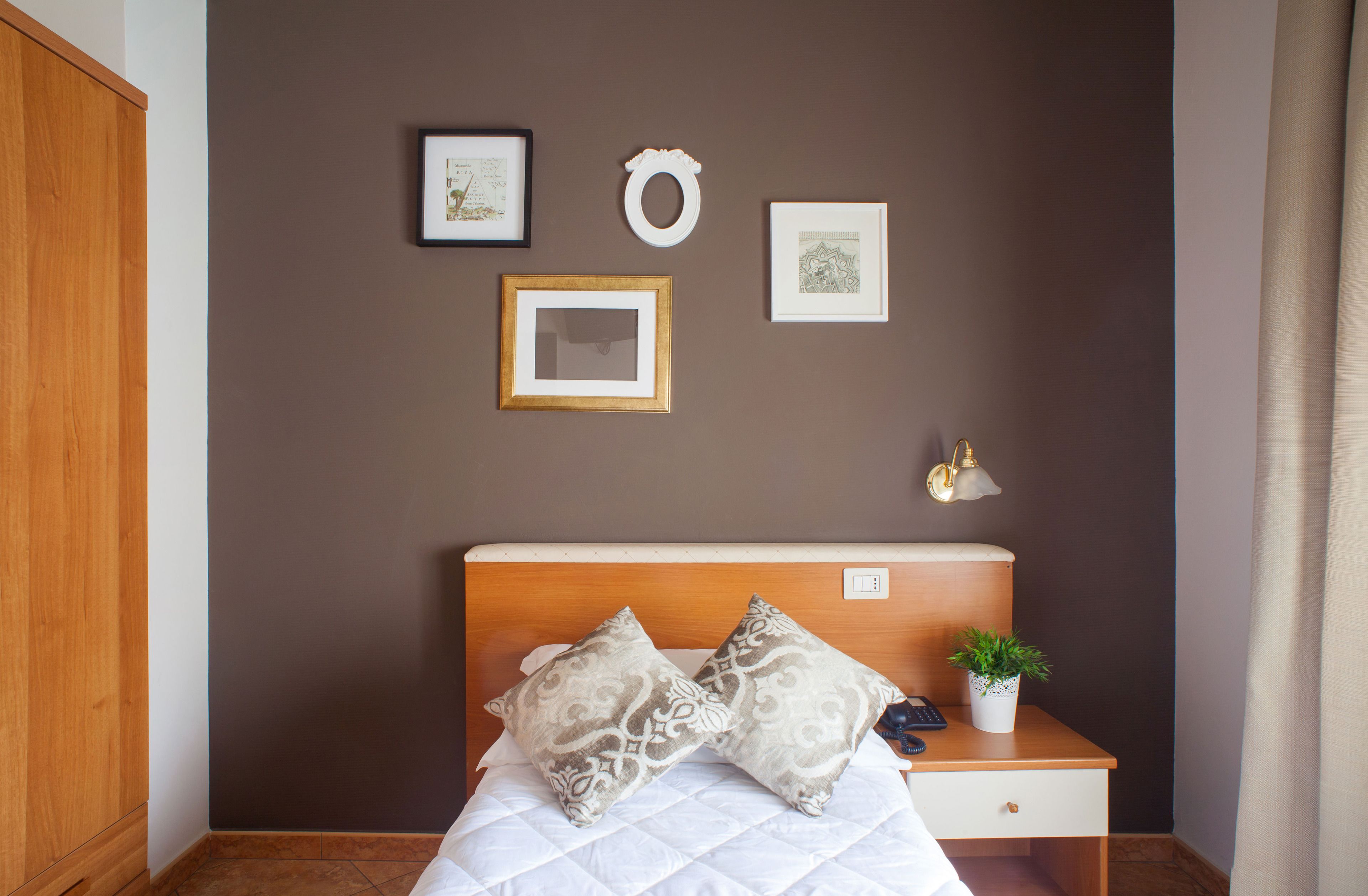 A neatly arranged bedroom with a bed, bedside table, and wall-mounted artwork.