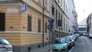 Una calle con coches aparcados y un edificio con el letrero 
