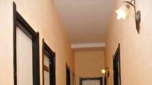 Un pasillo con suelo de madera, paredes color beige y puertas con marcos negros.