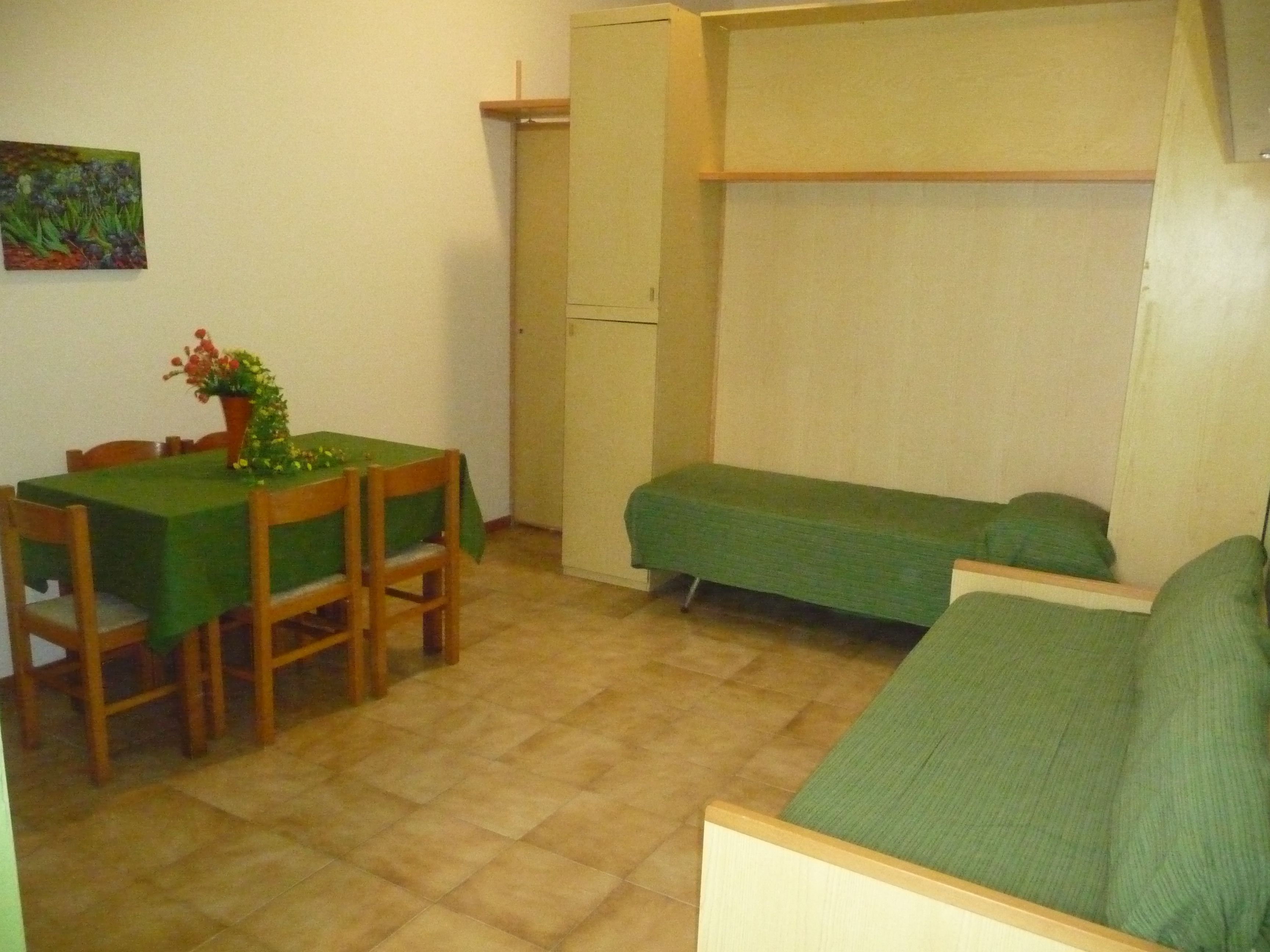 Una habitación pequeña con una mesa de comedor, sillas, un sofá y una cama individual.