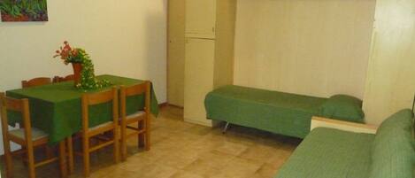Una habitación pequeña con una mesa de comedor, sillas, un sofá y una cama individual.