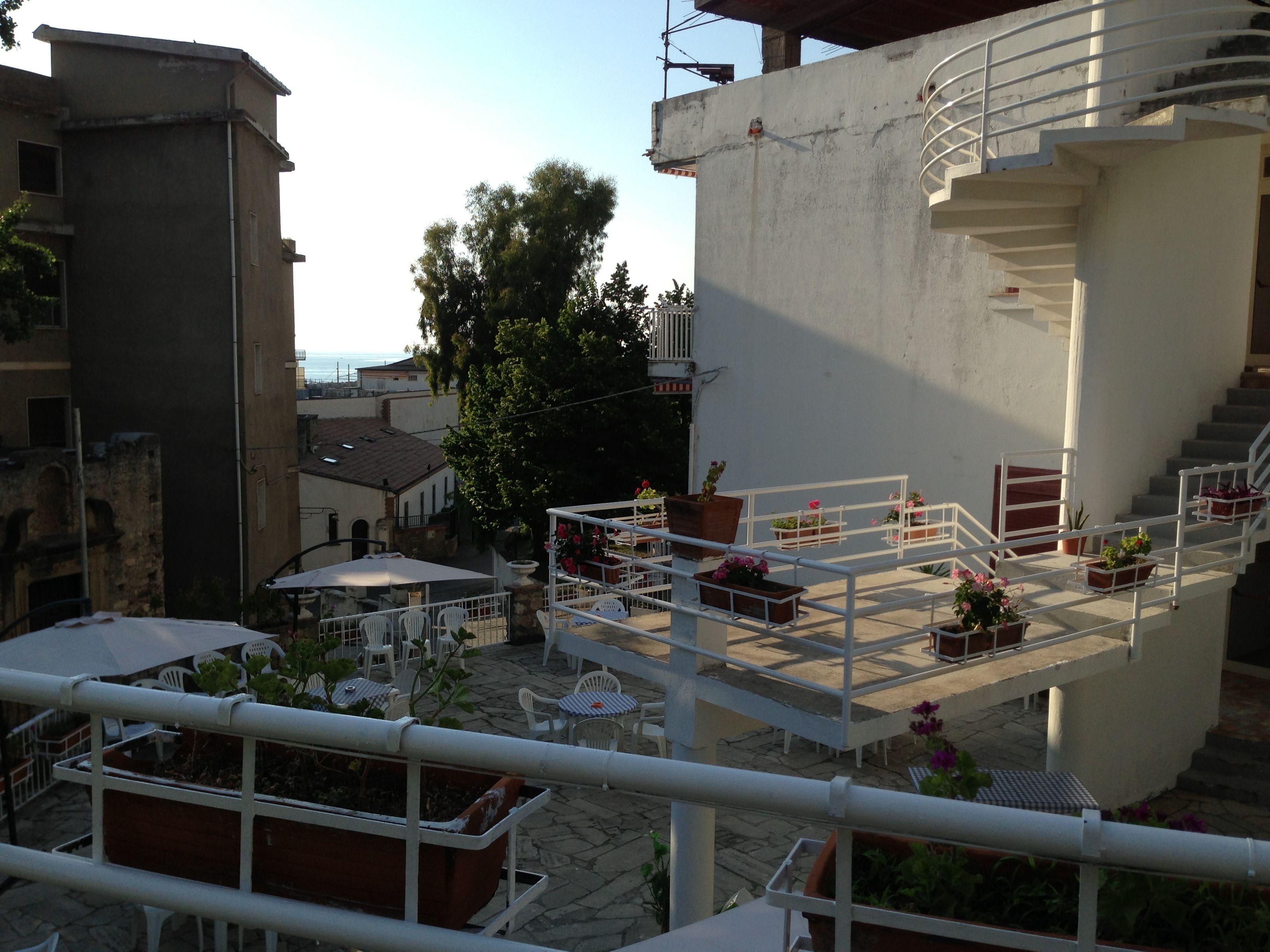 Une terrasse sur le toit, dotée d’un espace extérieur aménagé avec des plantes en pot et d’un escalier menant à un niveau supérieur.