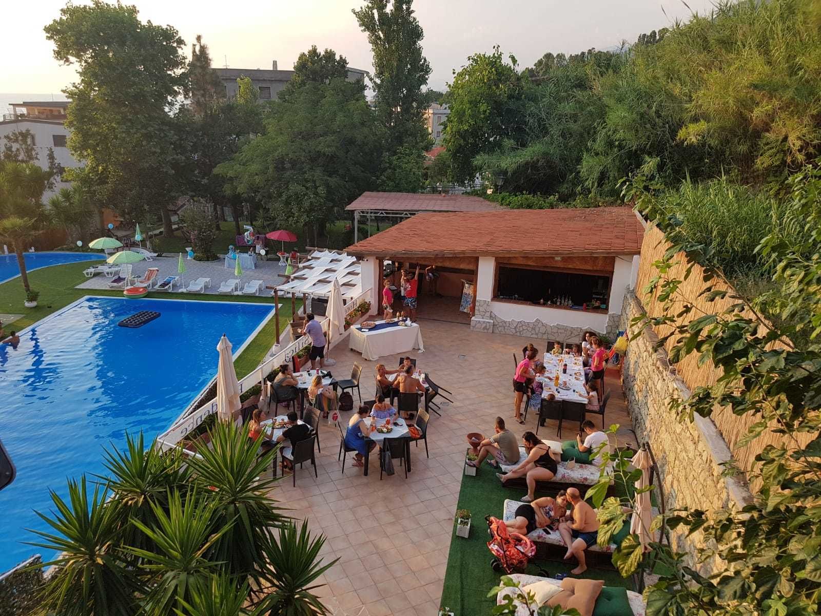 Zona junto a la piscina con asientos exteriores y un comedor techado.