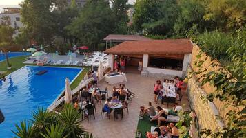 Zona junto a la piscina con asientos exteriores y un comedor techado.