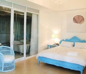 A bedroom with a bed, a nightstand, a lamp, a chair, and a sliding glass door. - The Heritage Baan Silom Hotel (Bangkok)