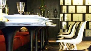 A dining area with a long table, multiple chairs, and a wall with framed pictures. - The Heritage Baan Silom Hotel (Bangkok)