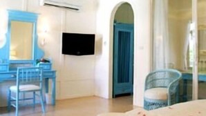 A bedroom with a bed, a desk, a chair, a television, and a bathroom with a shower. - The Heritage Baan Silom Hotel (Bangkok)