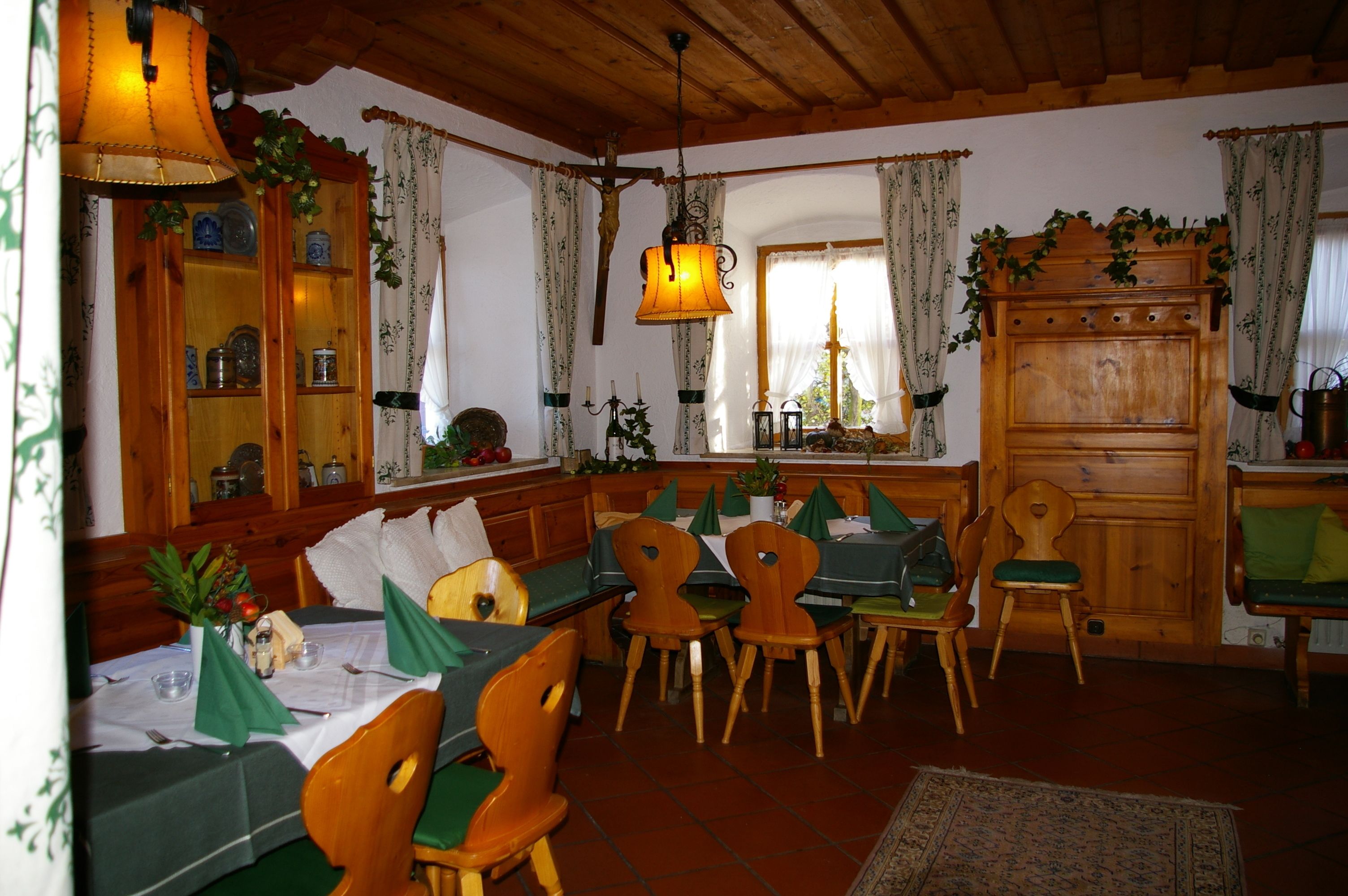 Un coin repas avec des meubles en bois, un lustre et une fenêtre agrémentée de rideaux.