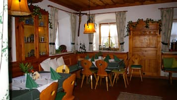 Un coin repas avec des meubles en bois, un lustre et une fenêtre agrémentée de rideaux.