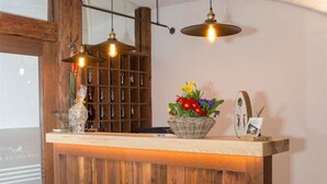 A wooden reception desk with a basket of flowers, a framed photo, and a shelf with keys. - Landgasthof Goldener Pflug (Frasdorf)