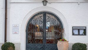 A building entrance with a large arched door, a signboard, and a potted plant. - Landgasthof Goldener Pflug (Frasdorf)