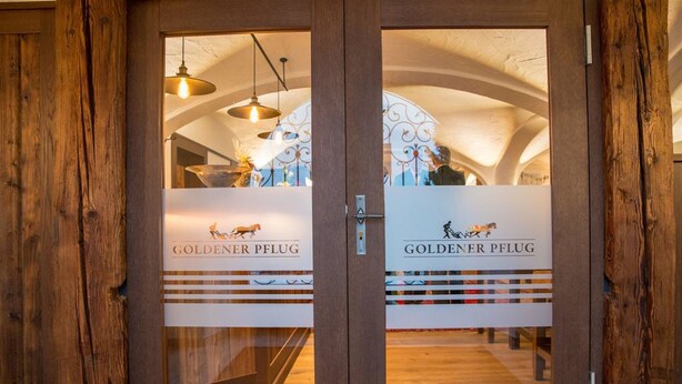 A wooden door with glass panels displaying the text "GOLDENER PFLUG" and a logo. - Landgasthof Goldener Pflug (Frasdorf)