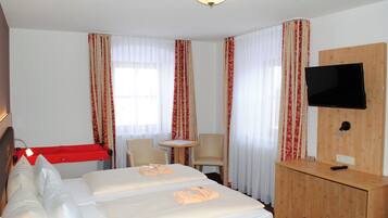 Habitación de hotel con dos camas, televisor, escritorio y una silla.