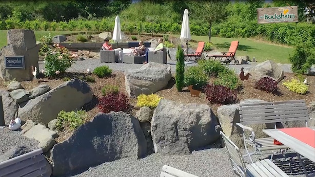 A garden area with outdoor seating, a sign for 'Zum Bockshahn', and a 'Saunagarten' sign. - Hotel und Landgasthof Zum Bockshahn (Spessart)