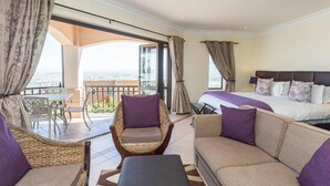 A hotel room with a balcony, a bed, a sofa, and a chair. - Blue Horizon Guest House (Cape Town)