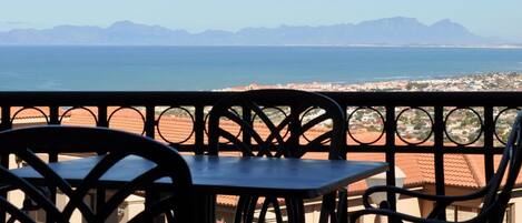 A balcony with a view of the sea and mountains.