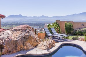 Área da piscina com espreguiçadeiras e vista para montanhas.