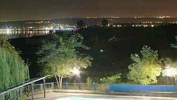 A swimming pool at night with surrounding trees and distant city lights. - Ulasan Hotel (Golbasi)