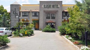 The entrance to Ulasam Hotel with a paved driveway, a parking area, and surrounding greenery. - Ulasan Hotel (Golbasi)