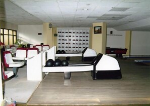 A bowling alley with multiple lanes, a seating area with chairs, and a shoe rack in the background. - Ulasan Hotel (Golbasi)