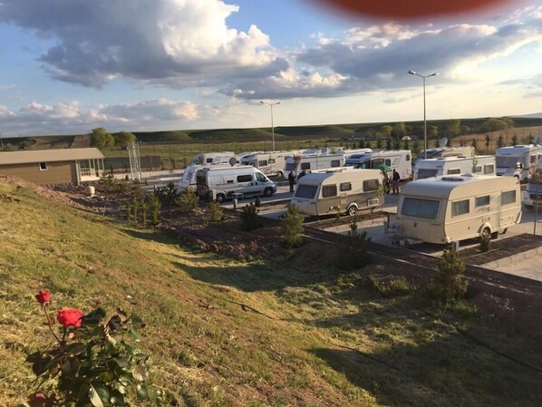 Un parque para caravanas con múltiples caravanas estacionadas en zonas delimitadas, rodeado de terreno cubierto de hierba y algunos árboles.