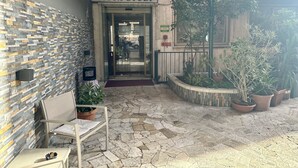 The entrance to Hotel Città Studi with a stone-tiled patio, a bench, and potted plants. - Hotel Città Studi (Milan)